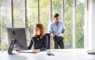 une jeune femme d'affaires travaille, écrit sur le papier ou le bloc-notes et rencontre le collègue du bureau au sujet de l'avenir de l'entreprise photo