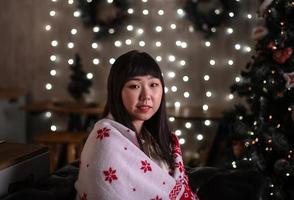 jolie fille coréenne aux cheveux noirs dans une salle de noël confortable avec des lumières bokeh festives le soir. portrait. photo