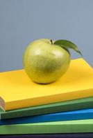 pomme sur le dessus d'une pile de livres, au dos des classes d'école. photo