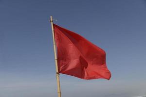 drapeau rouge se balançant au vent sur un fond de ciel bleu photo