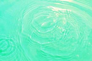 défocalisation floue transparente couleur bleue claire texture de surface de l'eau calme avec éclaboussures et bulle. fond de nature abstraite à la mode. vague d'eau au soleil avec espace de copie. aquarelle bleue brillante. photo