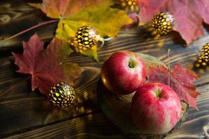 pommes mûres roses sur une table en bois avec des feuilles d'érable jaunes et rouges tombées. lumières de guirlandes, ambiance automnale chaleureuse et cosy, action de grâces, fête des récoltes. copie espace photo