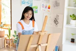 jeune fille peignant sur papier à la maison, cadre en bois, passe-temps et étude d'art à la maison. photo