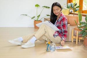 jeune fille assise sur le sol et peignant sur papier à la maison. passe-temps et étude d'art à la maison. photo