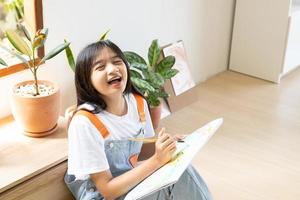 jeune fille assise sur le sol et peignant sur papier à la maison. passe-temps et étude d'art à la maison. photo