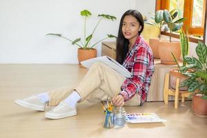 jeune fille assise sur le sol et peignant sur papier à la maison. passe-temps et étude d'art à la maison. photo