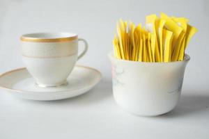 Sachet d'édulcorant substitut de sucre et tasse de thé sur fond blanc photo