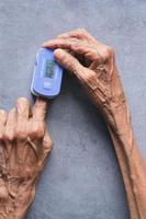 Main de jeunes femmes âgées à l'aide d'un oxymètre de pouls photo