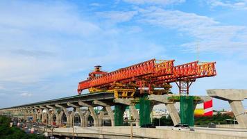 autoroute de la ville en construction avec d'énormes équipements mécaniques modernes. grande grue de machine lourde sur des piliers géants pendant la construction de la voie express. photo