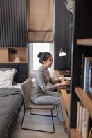 concept de travail à domicile une jeune fille avec un chignon faisant son travail à distance dans sa chambre photo
