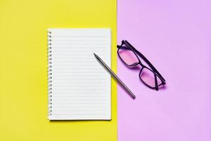 bloc-notes ou papier pour ordinateur portable avec stylo et lunettes sur rose jaune pour l'éducation et le concept d'entreprise photo