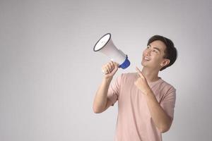 jeune homme souriant tenant un mégaphone sur studio de fond blanc. photo