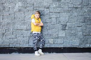 enfant mignon avec les bras croisés contre le mur. photo