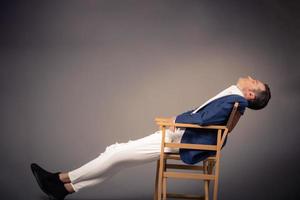 homme d'affaires reposant sur une chaise contre un mur vide. photo