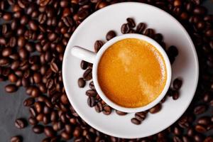 café noir frais chaud avec de la mousse de lait pour le menu du matin dans une tasse en céramique blanche avec des grains de café torréfiés. photo