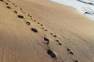 empreintes de pas dans le sable sur les rives de la mer méditerranée. photo