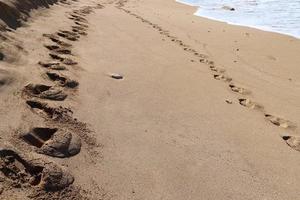 empreintes de pas dans le sable sur les rives de la mer méditerranée. photo