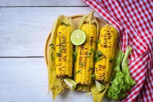 épis de maïs mûrs maïs sucré grillé pour un dîner ou une collation végétalien, nourriture de maïs sucré avec citron vert et coriandre, maïs sucré cuit sur fond de bois photo