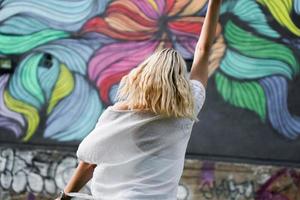 jolie jeune femme aux cheveux blonds debout dans une rue avec le mur de graffitis photo