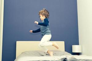 enfant ludique en pyjama s'amusant dans la chambre. photo