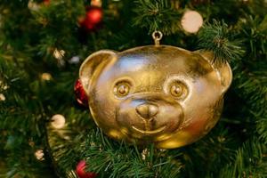 boule de sapin de noël en forme d'ours en peluche doré pn un sapin. carte de voeux festive pour les vacances d'hiver photo