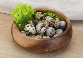 Oeufs de caille dans un panier sur fond de bois photo