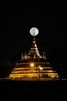 la super lune dans le ciel nocturne et la silhouette de l'ancienne pagode s'appelle wat ratchaburana, phitsanulok en thaïlande photo