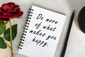 citation de motivation sur un carnet de notes avec tasse à café jetable, stylo et roses. photo