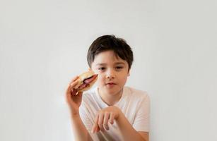 enfant en bonne santé mangeant des sandwichs au bacon faits maison avec des légumes mélangés, jeune garçon heureux prenant son petit déjeuner à la maison avant d'aller à l'école photo