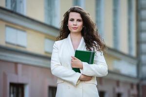le portrait d'une femme d'affaires avec un cahier à la main. fille élégamment habillée à l'extérieur. femme européenne blanche réussie photo