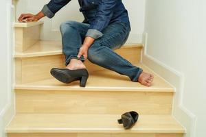 femme d'affaires asiatique douleur à la cheville, pied avec crampe à la jambe et chute dans les escaliers à cause des surfaces glissantes au bureau. photo