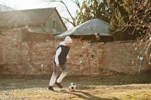 garçon joue avec le ballon de football en journée ensoleillée de printemps. photo