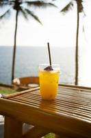 verre de jus d'orange frais sur la table supérieure bord de mer café vacances cocotiers arrière-plan. boire de l'eau été photo