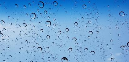 perspective de gouttelettes d'eau à travers la surface de la vitre contre le ciel bleu bon pour le contenu multimédia photo