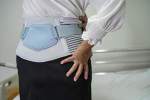 patiente asiatique portant une ceinture de soutien des maux de dos pour lombaire orthopédique avec marchette. photo