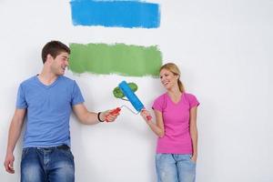 couple heureux peindre un mur dans une nouvelle maison photo