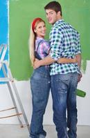 couple heureux peindre un mur dans une nouvelle maison photo