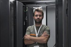 portrait d'un technicien masculin ou d'un administrateur réseau debout courageux comme un héros avec les bras croisés dans la salle des serveurs du centre de données. photo