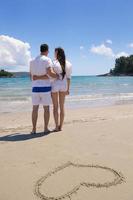 couple heureux s'amuser sur la plage avec coeur sur le sable photo