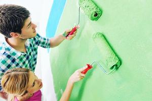couple heureux peindre un mur dans une nouvelle maison photo