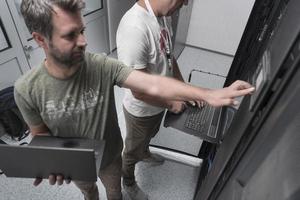 équipe de techniciens mettant à jour le matériel inspectant les performances du système dans la salle des super serveurs informatiques ou la ferme d'extraction de crypto-monnaie. photo