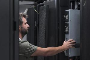 ingénieur informatique travaillant dans la salle des serveurs ou le centre de données, le technicien met dans un rack un nouveau serveur de superordinateur central d'entreprise ou de ferme minière de crypto-monnaie. photo