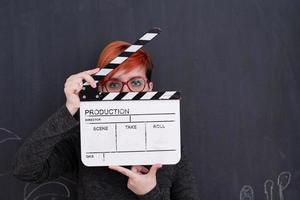 Redhead woman holding clapper sur fond noir photo