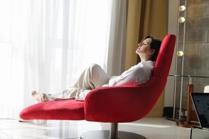 heureuse jeune femme se détendre à la maison sur un canapé photo