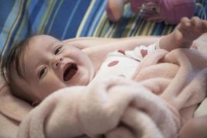 mignon petit bébé jouant avec les mains et souriant photo