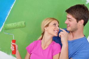 couple heureux peindre un mur dans une nouvelle maison photo