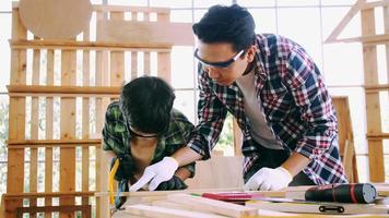 jeune charpentier masculin enseignant à son fils comment travailler le bois en atelier. photo