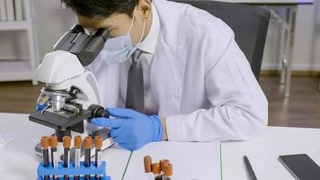 scientifique asiatique faisant des recherches et regardant à travers un microscope en laboratoire. photo
