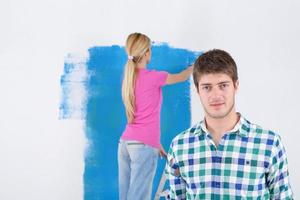 couple heureux peindre un mur dans une nouvelle maison photo