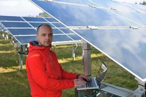 ingénieur utilisant un ordinateur portable sur le terrain de l'usine de panneaux solaires photo